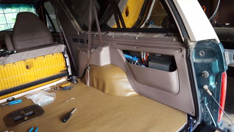 1996 Ford Bronco - The interior of a disassembled vehicle, likely an SUV, shows exposed yellow foam insulation under a seat and a brown carpeted floor. A dark…