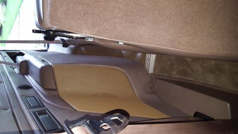 1996 Ford Bronco - Interior view of a vehicle's center console and the underside of a seat. Visible are seat adjustment mechanisms, a speaker grille, and what…