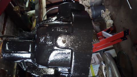 1996 Ford Bronco - A black, cast iron component, possibly a differential housing, is shown in a workshop setting. The component has raised lettering and a cir…