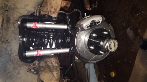 1996 Ford Bronco - A close-up view of a vehicle's front suspension and braking system, featuring new silver shocks with red logos, a black coil spring, and a…