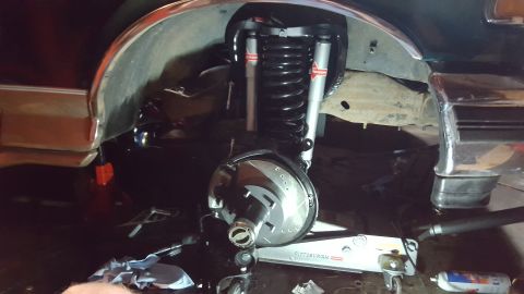 1996 Ford Bronco - A close-up view of the front suspension and braking system of a vehicle, likely a 1996 Ford Bronco, undergoing maintenance. The image shows…