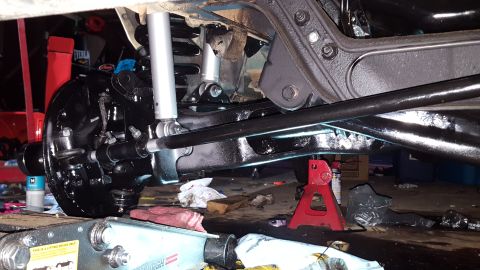 1996 Ford Bronco - The underside of a vehicle is shown, with a focus on the suspension and braking components. The parts are painted black and appear to be re…