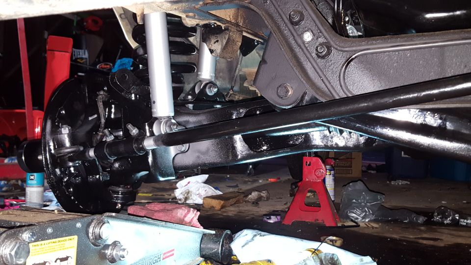 Underside of a vehicle showing black suspension components and new shocks.