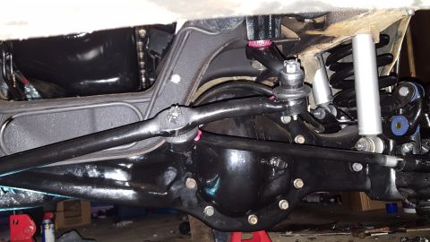 1996 Ford Bronco - A close-up view of the underside of a vehicle's rear axle and suspension system, featuring black painted components like the differential h…