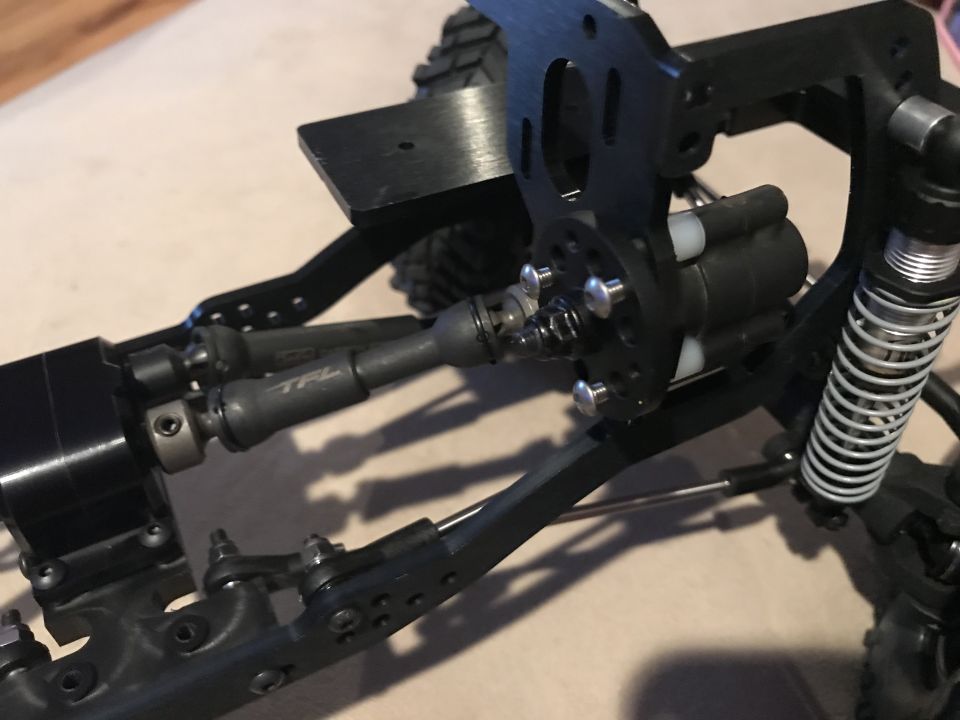 RC crawler drivetrain with TFL branded drive shafts and silver shock absorber.