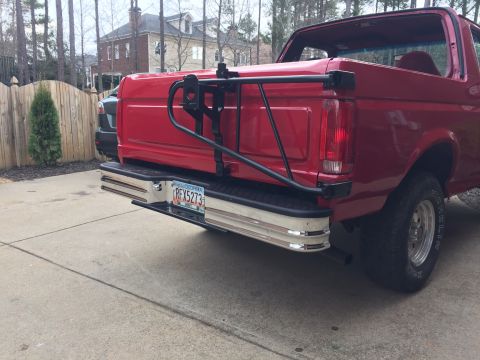 1994 Ford Bronco - Rear view of a red Ford Bronco with a black spare tire carrier mounted on the tailgate. The vehicle has a chrome bumper and a Georgia licen…