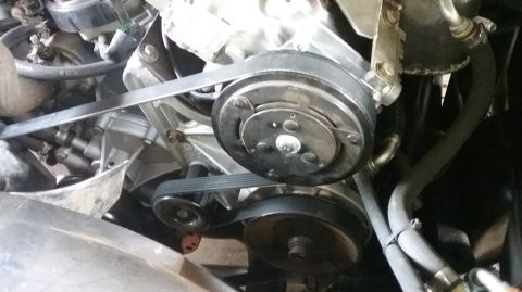 1995 Ford Bronco - A close-up view of the serpentine belt system in a 1995 Ford Bronco engine bay. The image shows the air conditioning compressor pulley, the…