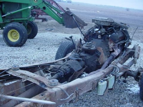 1992 Ford Bronco - Rusted vehicle chassis and engine are visible, with a green tractor in the background.
