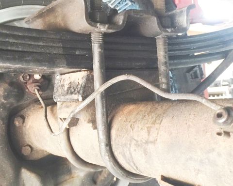 1994 Ford Bronco - A close-up view of the rear axle and leaf spring assembly of a vehicle, showing a brake line routed near the differential.