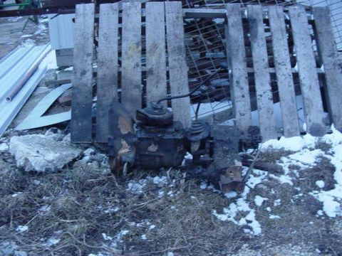 1992 Ford Bronco - Discarded vehicle transmission parts lie on the ground in the snow.
