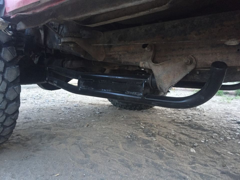 Underside of a red Ford Bronco with a black step bar installed.