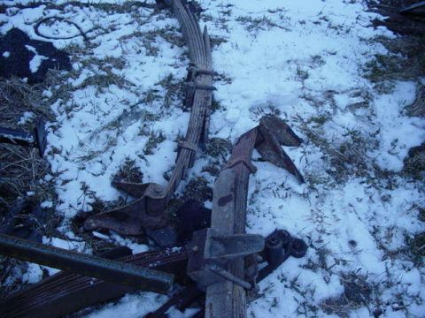 1992 Ford Bronco - Rusty leaf springs and suspension parts lie on the ground covered in snow.