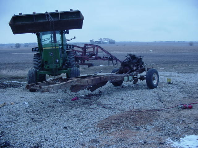 Tractor lifting a vehicle frame with engine attached