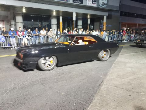 1969 Pontiac Firebird - A dark coupe with white wheels is parked outside at night.