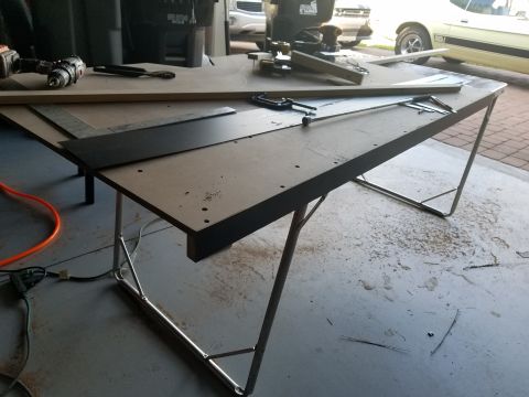 1994 Ford Bronco - A workbench is set up with tools and materials, with vehicles parked in the background.