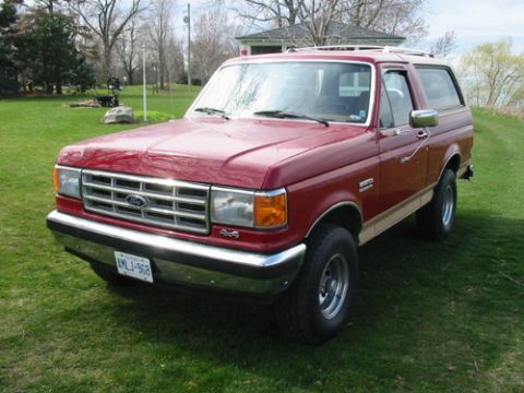 1988 Ford Bronco - This red Ford Bronco, likely a 1987 model, is shown from a three-quarter front angle on a sunny day.