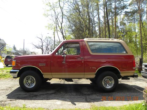 1988 Ford Bronco - This 1988 Ford Bronco is seen from the side, its distinctive two-tone red and tan paint scheme and a roof rack.