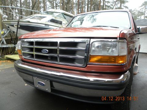 1988 Ford Bronco - This Ford truck features a prominent chrome grille and bumper, with a boat visible behind it.