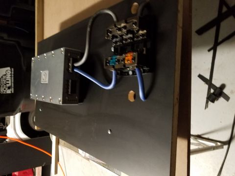 1994 Ford Bronco - A car stereo amplifier and associated wiring are mounted on a black panel, with a partial view of a speaker and other components in the bac…