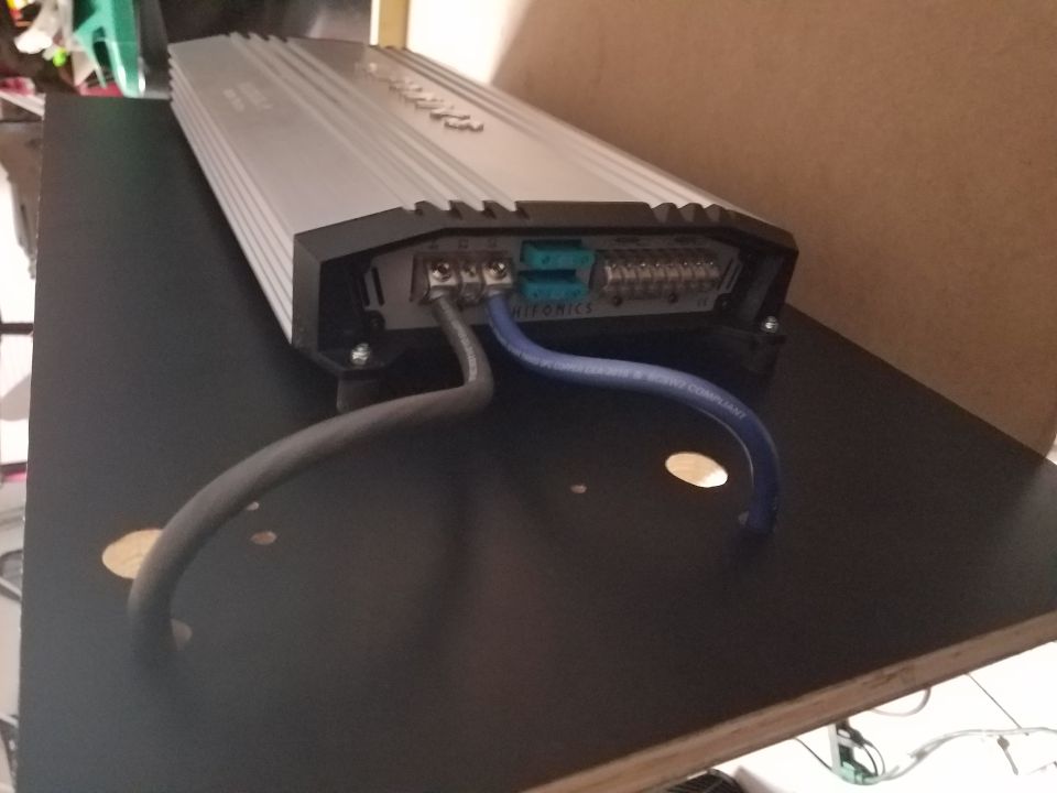 Car amplifier with power and speaker wires connected to terminals