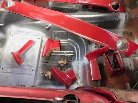 1968 Mercury Cougar - Various red interior trim pieces are laid out inside a car's cabin, suggesting a restoration project.