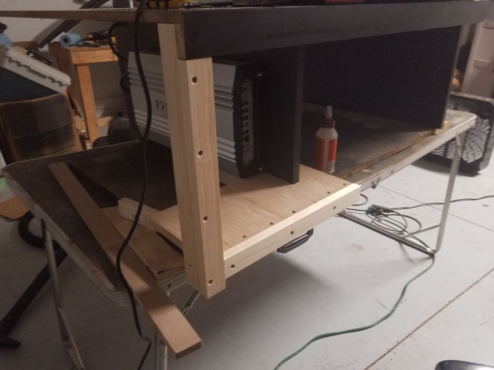 car amplifier mounted in a wooden enclosure on a workbench