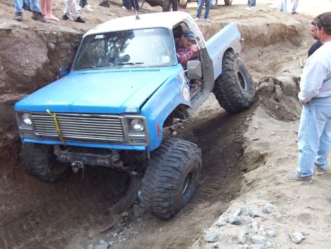 2000 Ford F-450 - Modified pickup truck with oversized tires is stuck in a deep dirt trench.