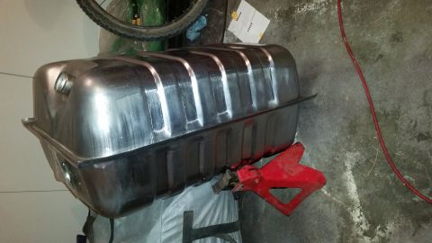 1985 Ford Bronco - A clean, unpainted metal fuel tank is supported by a red jack stand on a concrete floor. The tank has a ribbed top and appears to be a repl…