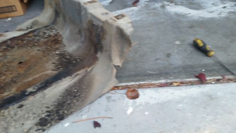 1985 Ford Bronco - A heavily rusted and damaged metal part, possibly from a vehicle's undercarriage, lies on a concrete surface next to a screwdriver. The par…