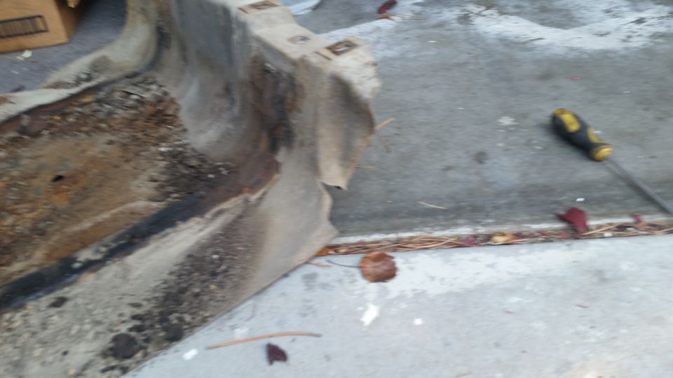 Rusted vehicle part on concrete with a screwdriver