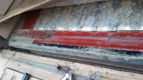 1985 Ford Bronco - This image shows the interior of a vehicle, focusing on the lower section of the rear passenger side door jamb area. There is visible rust…