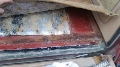 1985 Ford Bronco - The image shows significant rust and corrosion on the floor pan of a vehicle, likely a classic SUV, with the carpet pulled back to reveal t…