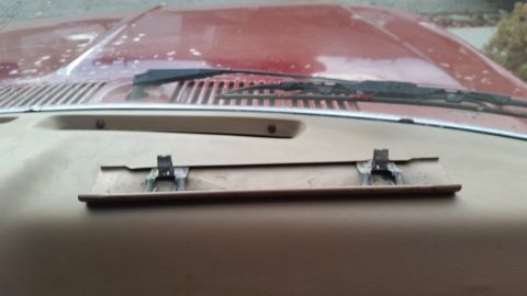 1985 Ford Bronco - The interior of a vehicle shows a tan dashboard with a metallic bracket attached to a recessed panel. The hood and windshield wipers are vi…