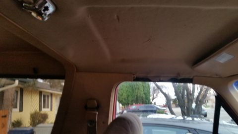 1985 Ford Bronco - Interior view of the headliner and sun visor in a vehicle, looking out the windows at a residential street.