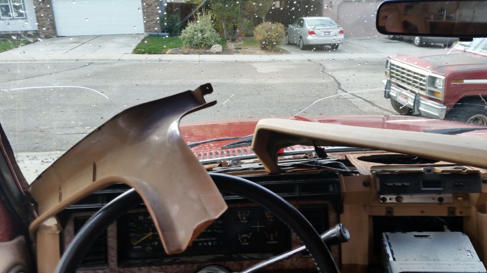 Interior of a vintage Ford truck with a cracked windshield showing another red Ford truck outside.