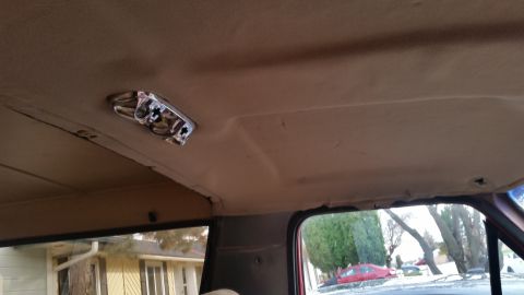 1985 Ford Bronco - The interior of a vehicle shows the headliner with a chrome dome light fixture. The view looks towards the front of the vehicle and out the…
