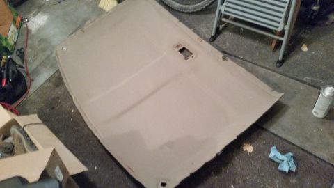1985 Ford Bronco - The headliner has been removed from the vehicle and is resting on the floor, showing its internal structure and mounting points.