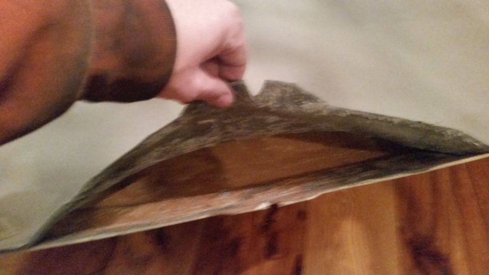 Hand pulling down a detached, sagging headliner inside a vehicle