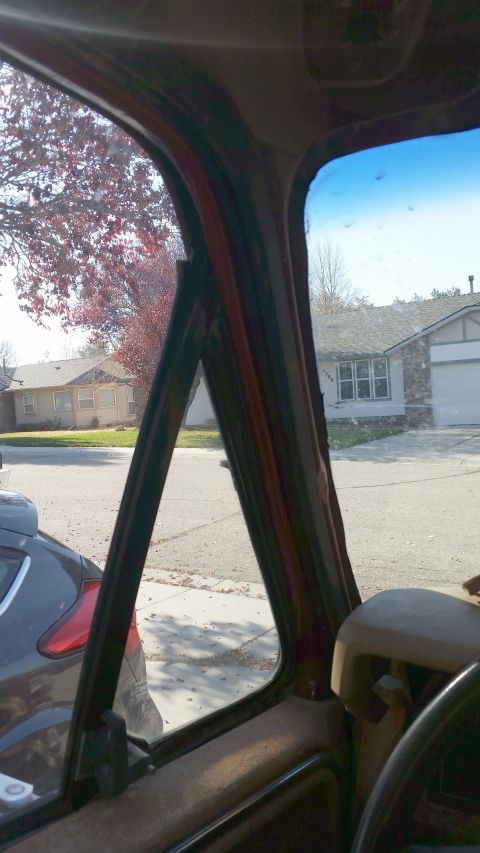 1985 Ford Bronco - View from inside a vehicle's cabin, looking out through the door frame and window.