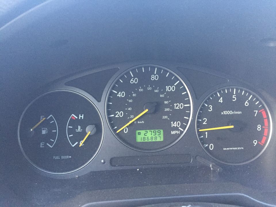 Car dashboard with speedometer, tachometer, fuel, and temperature gauges. Odometer shows 2799 and 186887 miles.
