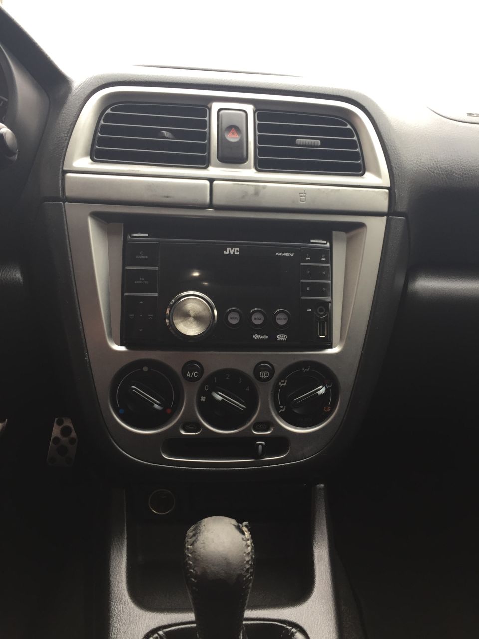 Car dashboard interior with JVC stereo, air vents, climate controls, and gear shifter.