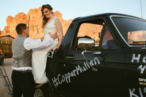 1988 Ford Bronco - A wedding couple poses next to a black truck with custom spray-painted text.
