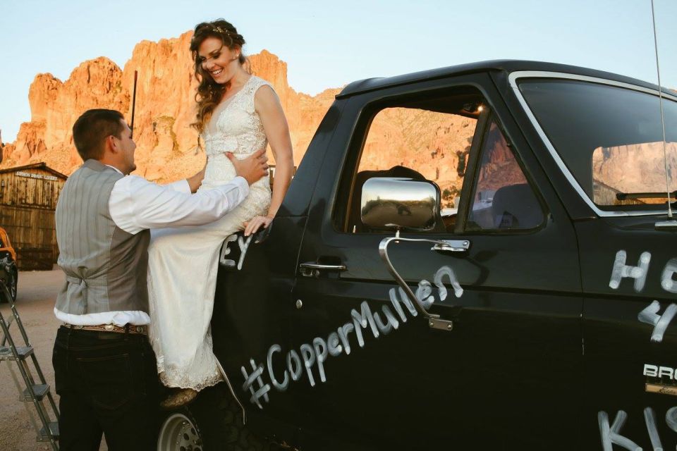 Bride and groom by a black truck with "#CopperMullen" spray-painted on the side