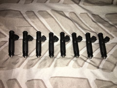 1996 Ford Bronco - A set of eight fuel injectors are displayed on a textured fabric background.