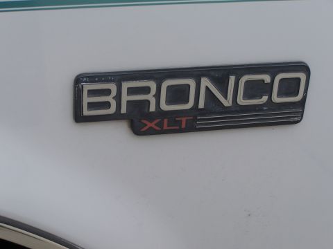 1995 Ford Bronco - Close-up of a Bronco XLT emblem on a white vehicle.