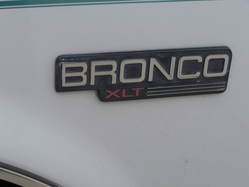 Bronco XLT emblem on white vehicle body