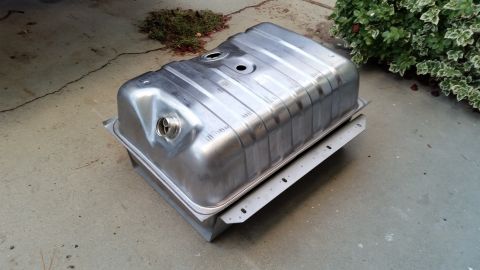 1985 Ford Bronco - A new metal gas tank, likely for a classic vehicle, sits on a concrete surface next to some greenery.