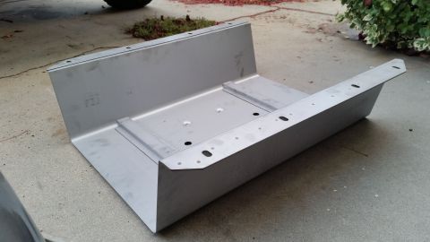 1985 Ford Bronco - This metal assembly, likely a fuel tank, is shown from a low angle on a concrete surface.