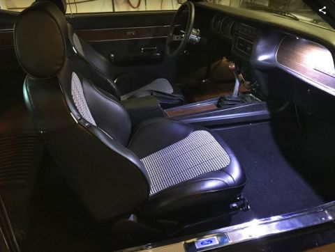 1969 Mercury Cougar - The interior of a 1969 Mercury Cougar features houndstooth patterned seats and woodgrain accents on the dashboard and center console.