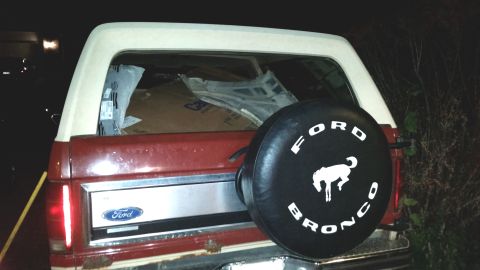 1985 Ford Bronco - The rear of a red Ford Bronco is shown with a spare tire cover.